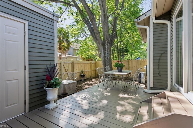 wooden terrace with outdoor dining area and a fenced backyard