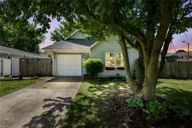 view of home's exterior with a lawn, fence, a shingled roof, concrete driveway, and an attached garage