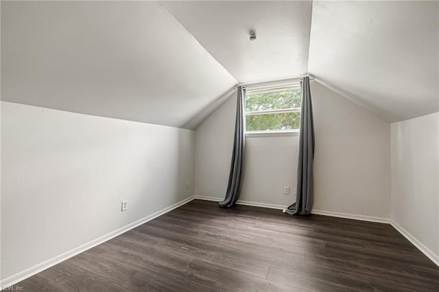 additional living space featuring baseboards, vaulted ceiling, and dark wood-type flooring