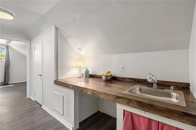 kitchen featuring a sink, butcher block countertops, lofted ceiling, dark wood-type flooring, and visible vents