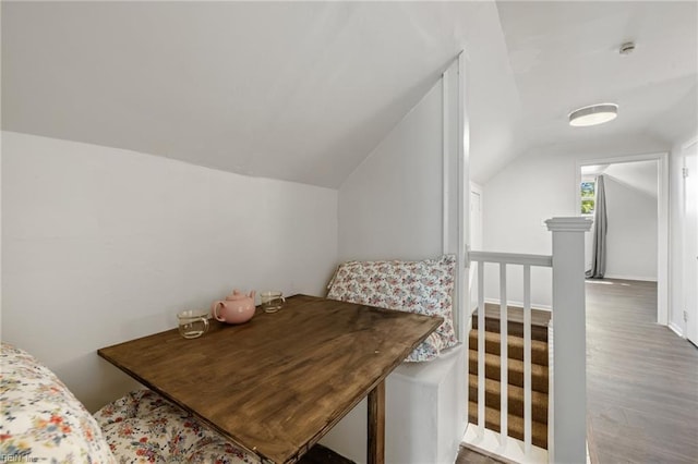 interior space with an upstairs landing, wood finished floors, and lofted ceiling