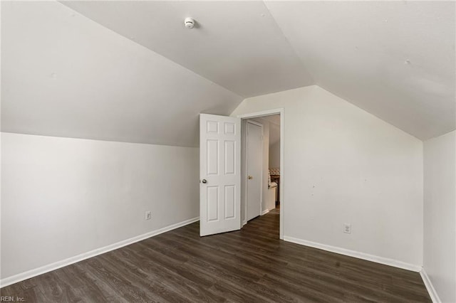 additional living space with baseboards, dark wood-style flooring, and lofted ceiling