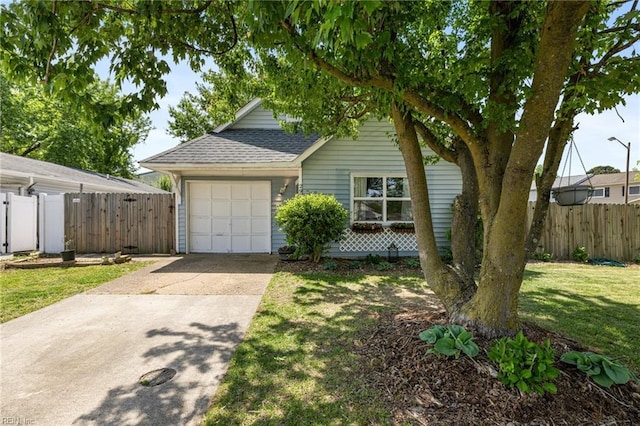 exterior space featuring a garage, a front lawn, fence, a shingled roof, and concrete driveway
