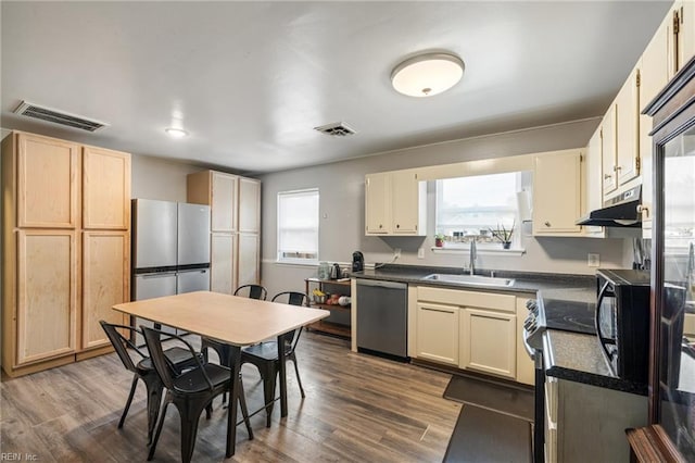 kitchen with a sink, under cabinet range hood, stainless steel appliances, and visible vents