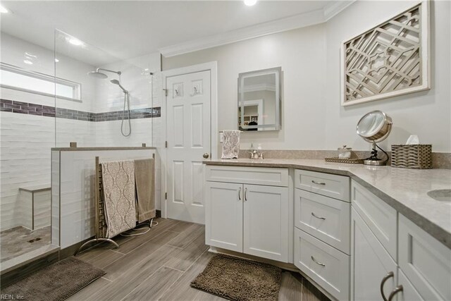 828 Vanderbilt Ave, Virginia Beach, VA 23451 - bathroom with double vanity, wood tiled floor, a tile shower, a sink, and ornamental molding