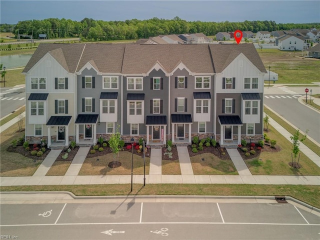 townhome / multi-family property with board and batten siding, a standing seam roof, metal roof, uncovered parking, and stone siding