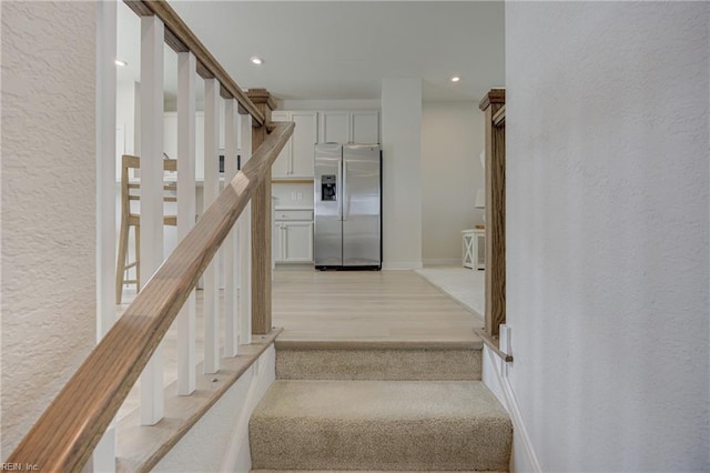 stairs featuring baseboards, recessed lighting, a textured wall, and wood finished floors