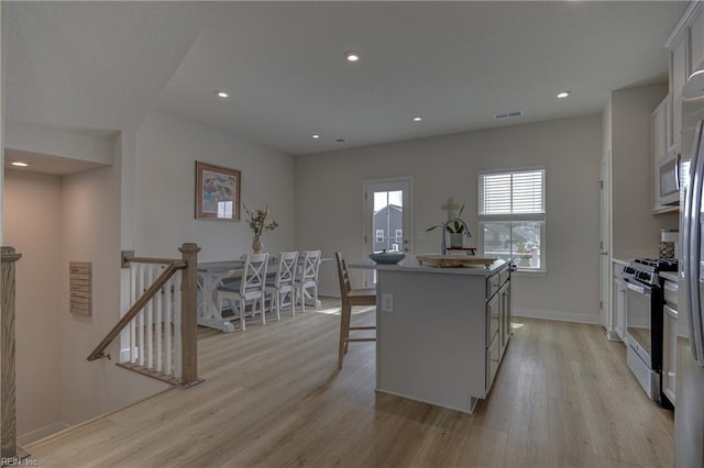 kitchen featuring visible vents, a center island with sink, light wood finished floors, range with gas stovetop, and recessed lighting