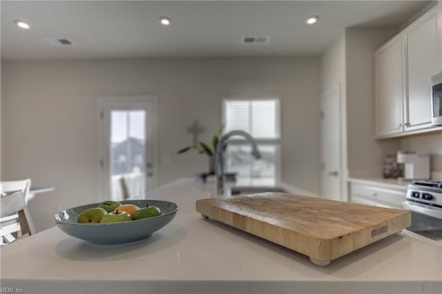 kitchen featuring a kitchen island, white cabinetry, a sink, and light countertops