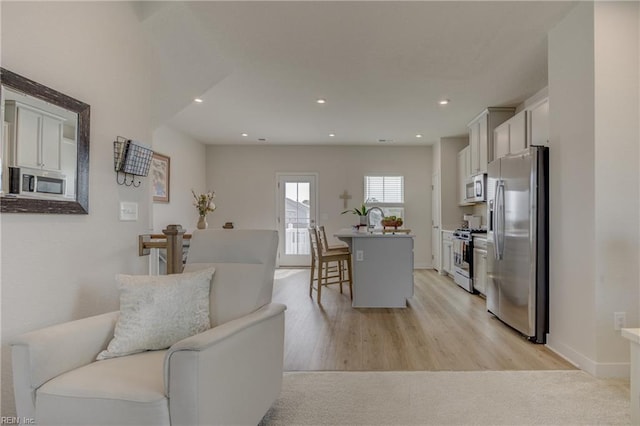 living room featuring recessed lighting, baseboards, and light wood-style flooring