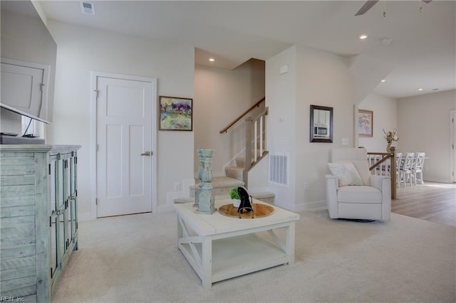 living area featuring a ceiling fan, light colored carpet, and visible vents