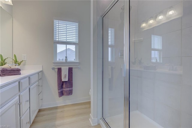 bathroom with vanity, baseboards, a shower stall, and wood finished floors
