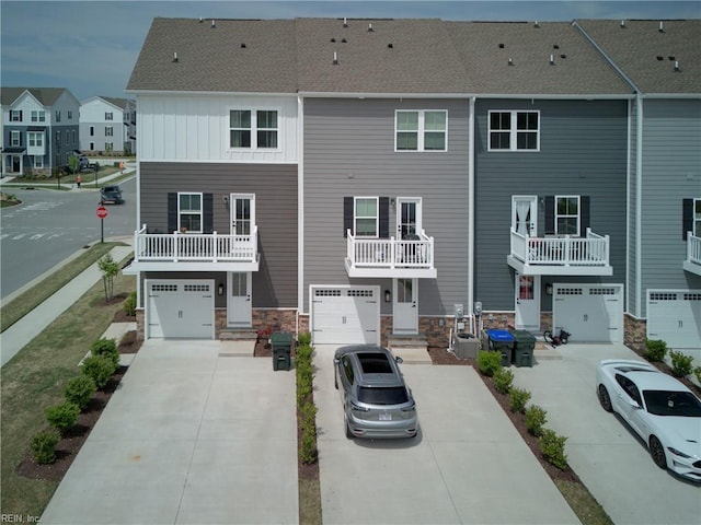 view of front of house with an attached garage, driveway, a residential view, and stone siding