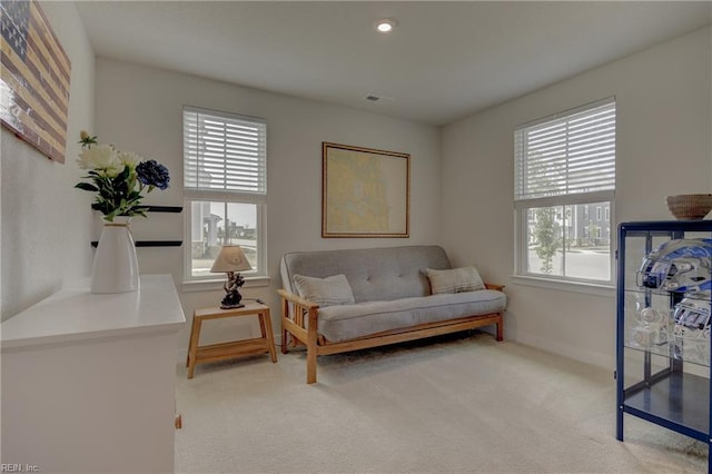 living area with baseboards, visible vents, and light carpet