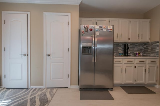 kitchen featuring white cabinets, backsplash, stainless steel fridge, and light countertops