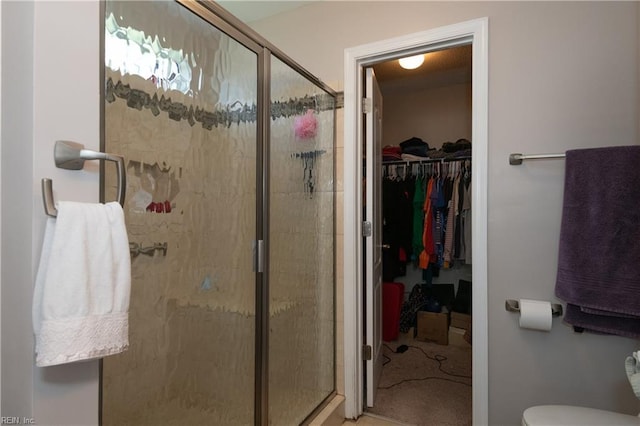full bathroom featuring toilet, a walk in closet, and a stall shower