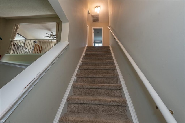 staircase with plenty of natural light, a ceiling fan, and visible vents