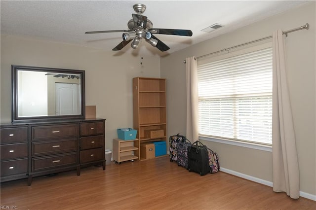 bedroom featuring baseboards, a ceiling fan, wood finished floors, and visible vents