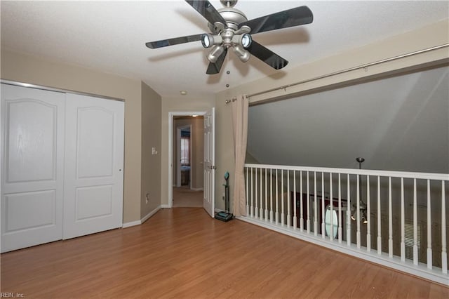 unfurnished bedroom featuring baseboards, ceiling fan, a closet, and wood finished floors