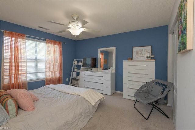 bedroom featuring a ceiling fan, visible vents, and light carpet