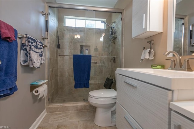 bathroom with vanity, baseboards, toilet, and a shower stall