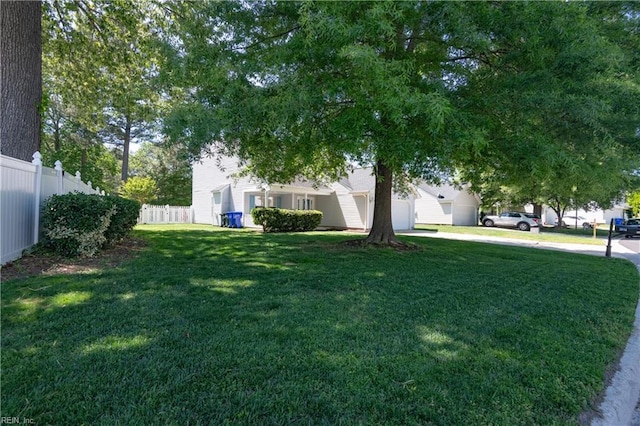 view of yard with an attached garage, fence, and concrete driveway