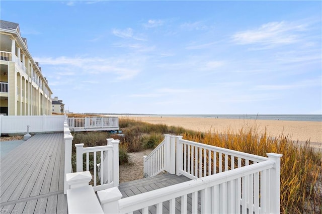 wooden deck featuring a water view and a view of the beach