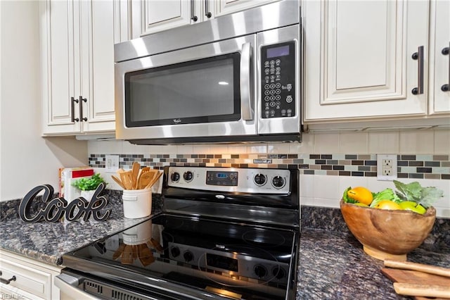 kitchen featuring dark stone counters, appliances with stainless steel finishes, decorative backsplash, and white cabinetry