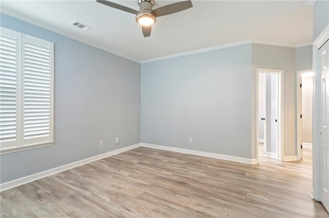 empty room with visible vents, ornamental molding, light wood-style flooring, and ceiling fan