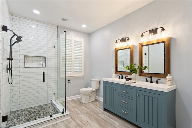 full bath with double vanity, visible vents, a shower stall, wood finished floors, and toilet
