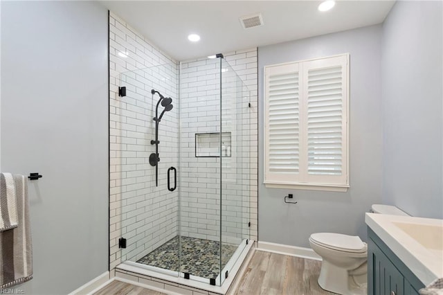 bathroom featuring a shower stall, toilet, wood finished floors, and visible vents