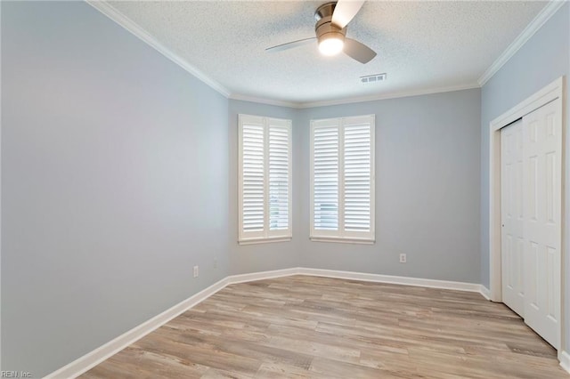 unfurnished bedroom with light wood-style floors, ornamental molding, a textured ceiling, and visible vents