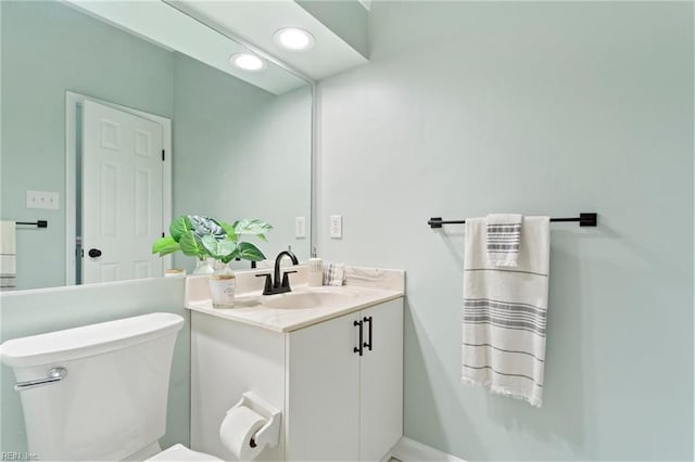 half bathroom featuring toilet, baseboards, recessed lighting, and vanity