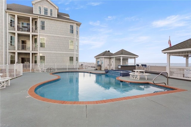 view of swimming pool with a pool with connected hot tub, fence, and a patio area