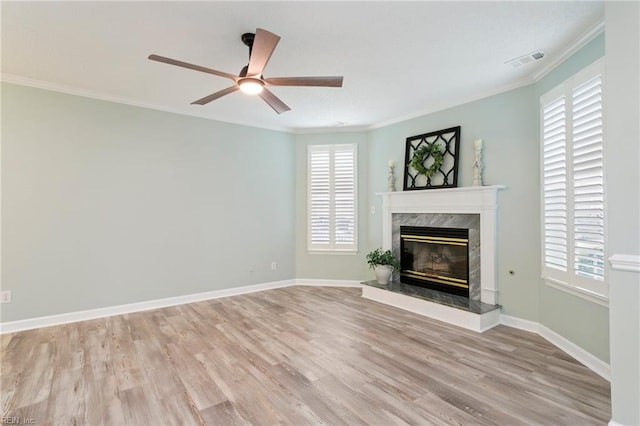 unfurnished living room with light wood finished floors, a fireplace, a ceiling fan, visible vents, and ornamental molding
