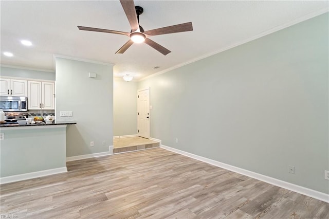 unfurnished living room with crown molding, light wood-style floors, ceiling fan, and baseboards
