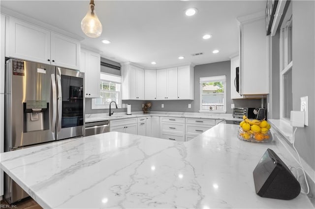 kitchen featuring white cabinets, appliances with stainless steel finishes, light stone counters, recessed lighting, and visible vents