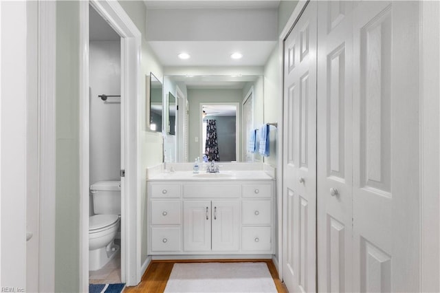 bathroom featuring vanity, recessed lighting, wood finished floors, and toilet