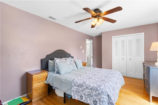 bedroom with ceiling fan, visible vents, light wood-style flooring, and a closet