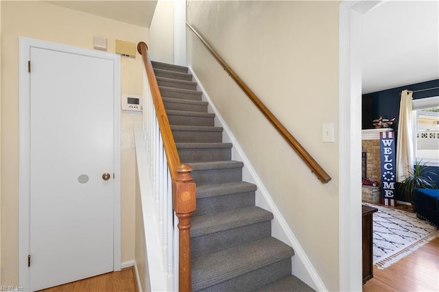 staircase featuring wood finished floors and a fireplace