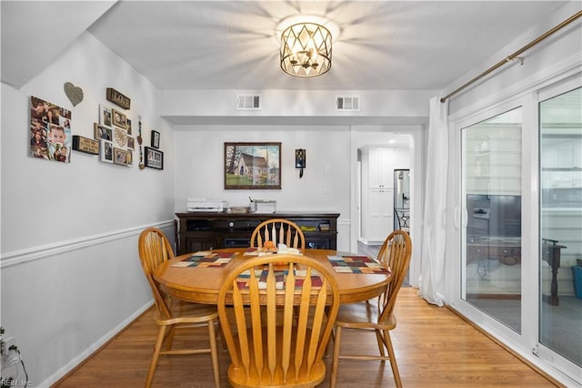dining area featuring a notable chandelier, visible vents, baseboards, and light wood finished floors