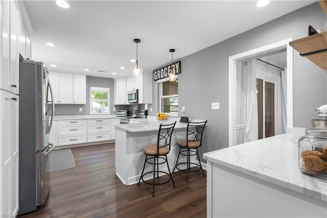 kitchen with white cabinets, stainless steel appliances, recessed lighting, a peninsula, and dark wood-type flooring