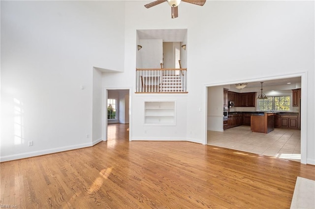 419 Hastings Pl, Suffolk, VA 23433 - unfurnished living room featuring built in features, a high ceiling, baseboards, and light wood-type flooring