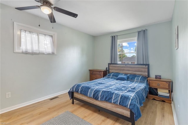 bedroom featuring ceiling fan, baseboards, visible vents, and wood finished floors