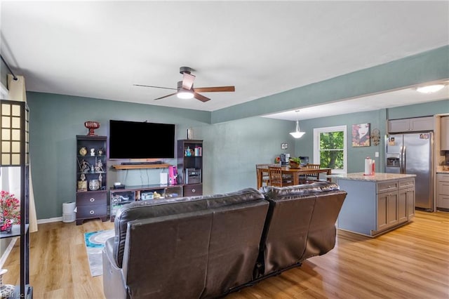 living area featuring light wood-style floors and a ceiling fan