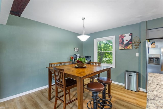 dining space with baseboards and light wood finished floors