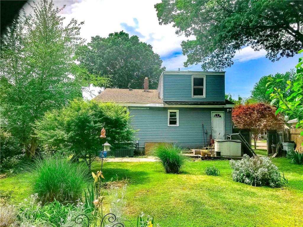 rear view of property featuring a yard, fence, and a chimney