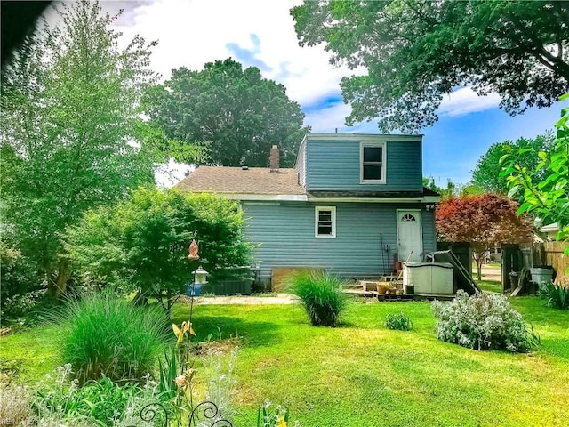 rear view of property featuring a yard, fence, and a chimney