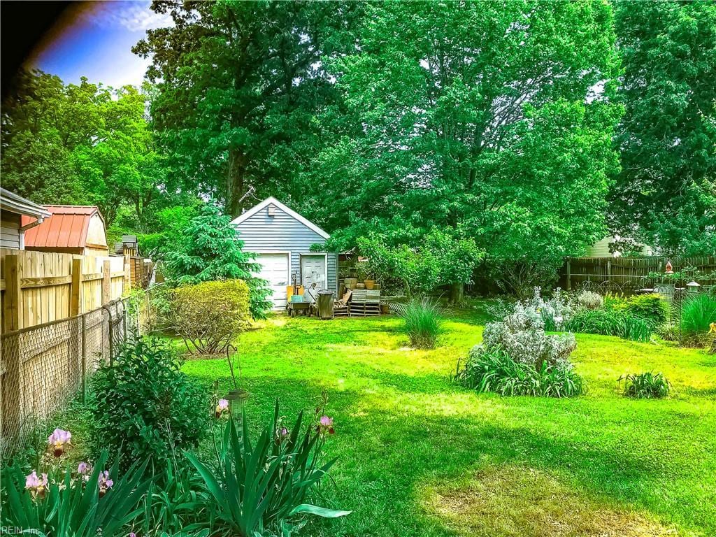 view of yard featuring a fenced backyard, a detached garage, and an outdoor structure