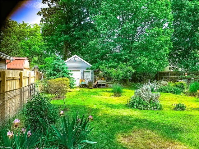 view of yard featuring a fenced backyard, a detached garage, and an outdoor structure